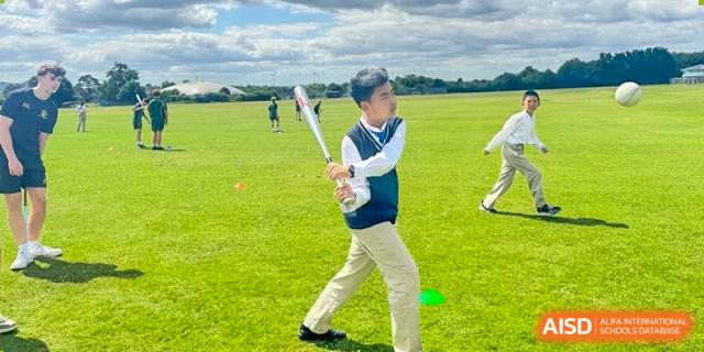 A student holding a baseball bat, practicing batting outdoors on a field at Suzhou Science and Technology Town Foreign Language High School.