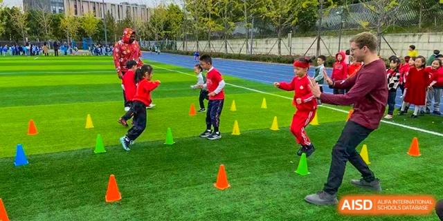 Young students in red uniforms participating in an outdoor sports drill with cones at Suzhou Science and Technology Town Foreign Language High School.