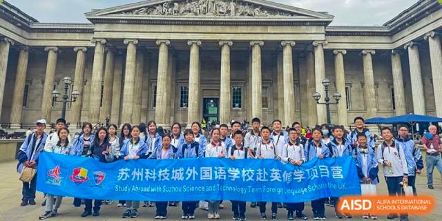 A group of students posing in front of a classical building with columns during a trip. Suzhou Science and Technology Town Foreign Language High School.