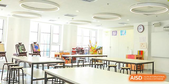 The bright and airy cafeteria or common area at Dehong Beijing International Chinese School with many tables and large windows.