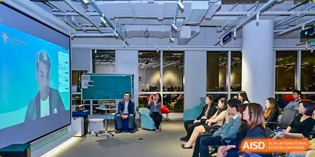 A formal presentation or seminar being held for adults at Dehong Beijing International Chinese School in a modern, well-lit space.