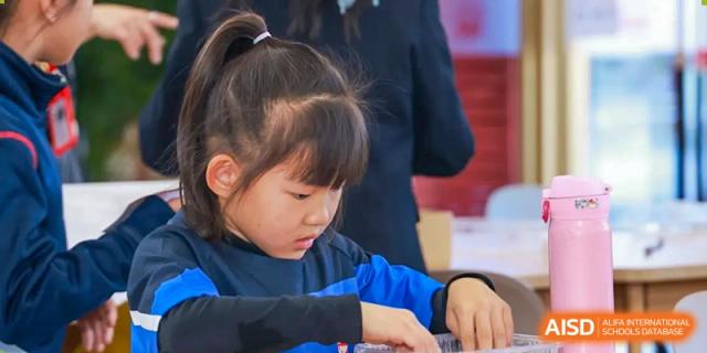 A young female student at Dehong Beijing International Chinese School is focused on a hands-on learning activity in class.
