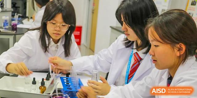 Female students at Dehong Beijing International Chinese School working together on a science experiment in the school's lab.