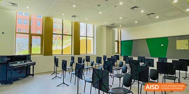 A bright, organized music classroom or auditorium at Dehong Beijing International Chinese School with rows of chairs and stands.