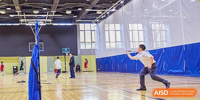 Students playing basketball in the spacious indoor gymnasium at Dehong Beijing International Chinese School, practicing shots.
