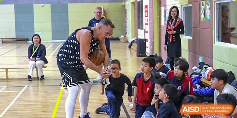 A basketball player or coach at Dehong Beijing International Chinese School teaching young students drills and ball handling techniques.