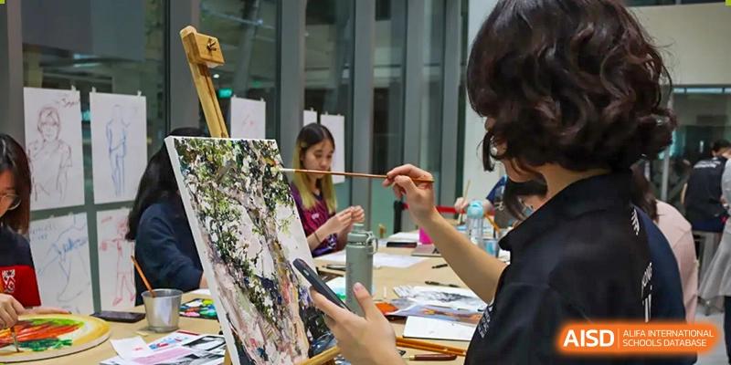 A student at Dehong Beijing International Chinese School focused on painting a picture during an art class or workshop.