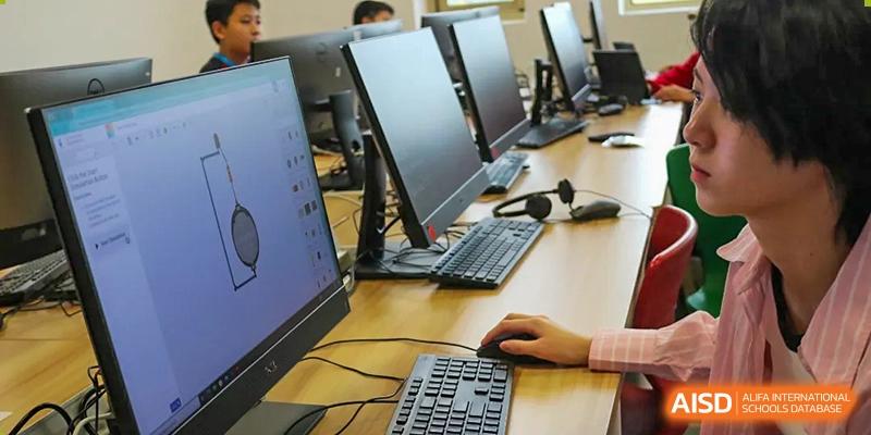 A close-up of a student at Dehong Beijing International Chinese School working on a computer in a modern classroom or lab.