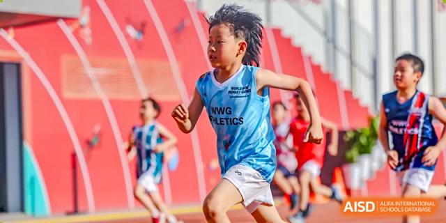A young student from Dehong Beijing International Chinese School runs fast during a race on a red track during a sports day.