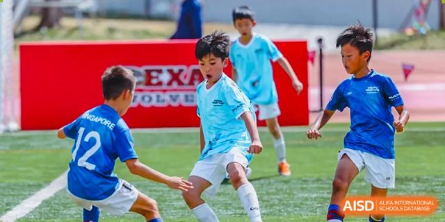 Students from Dehong Beijing International Chinese School competing for the ball during an energetic outdoor football (soccer) match.