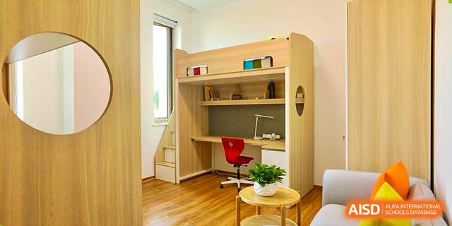 A student's dormitory room at Dehong Beijing International Chinese School featuring a loft bed, desk, and modern furniture.