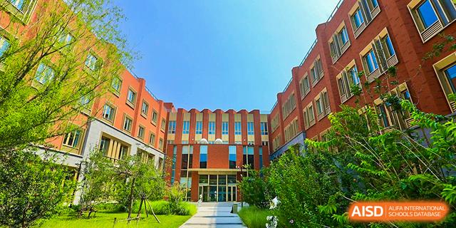 The striking red brick exterior of the main building at Dehong Beijing International Chinese School on a sunny day.