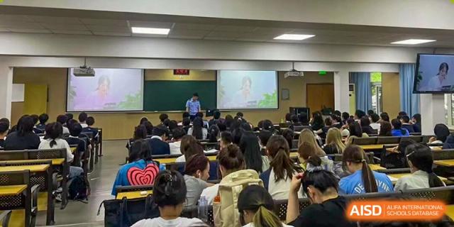 Students are seated close together, facing the front where a screen displays content at Cambridge International School Litai College. SISU.