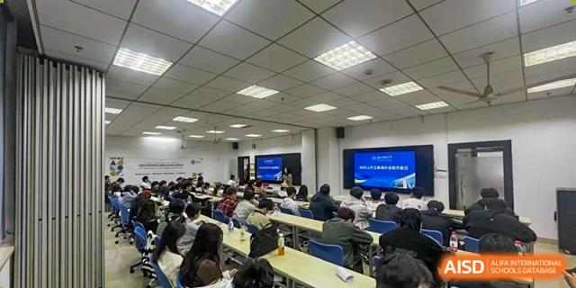 Students are listening in a large lecture room with rows of desks and a screen at the front at Cambridge International School Litai College. SISU.