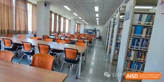 An image of a quiet, empty study room or library with tables, orange chairs, and bookshelves at Cambridge International School Litai College. SISU.