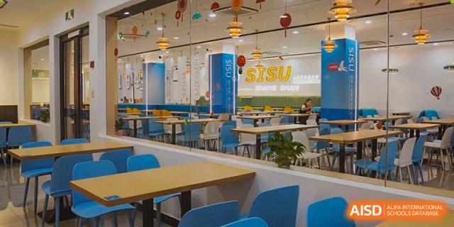 A brightly lit, colorful student dining hall or canteen with blue chairs, tables, and the 'SISU' sign at Cambridge International School Litai College. SISU.