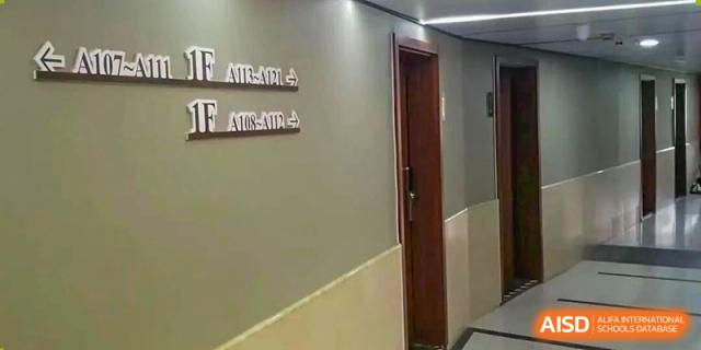 A plain hallway with a closed door and signs indicating floor levels (1F/2F) mounted on the wall at Cambridge International School Litai College. SISU.