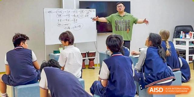 Students in uniform sit in a circle during a classroom discussion led by a teacher at a whiteboard at the Shenzhen Academy of International Education.
