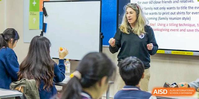 An instructor leads an interactive group session with students in a bright, well-equipped classroom at the Shenzhen Academy of International Education.