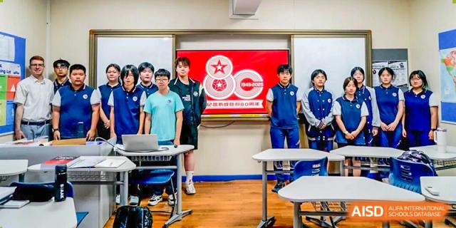 A group of students in uniform standing in a classroom during a presentation at the Shenzhen Academy of International Education.