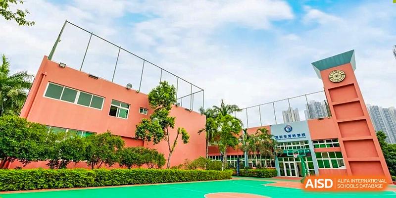 The bright pink exterior of the campus buildings viewed from the outdoor sports courts surrounded by greenery at Shenzhen Academy of International Education.