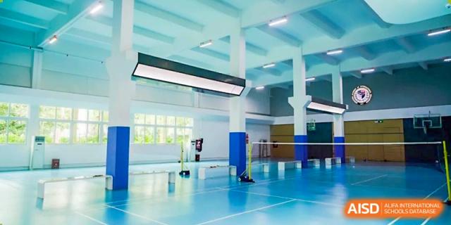 An expansive, brightly lit indoor sports gymnasium featuring professional blue flooring and badminton nets at Shenzhen Academy of International Education.