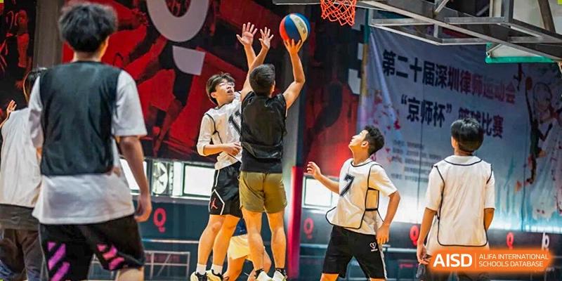 Students jump for a rebound during a competitive basketball game held in the school's indoor athletic facility at Shenzhen Academy of International Education.