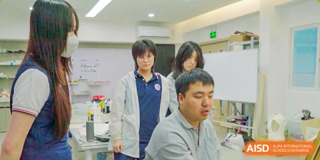 A group of students collaborating closely on a technical project inside a bright, modern science laboratory environment at Shenzhen Academy of International Education.