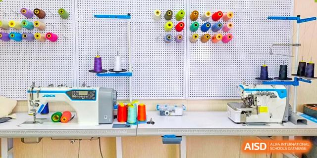 A professional sewing workspace featuring a sewing machine and colorful thread spools organized on a white pegboard at Shenzhen Academy of International Education.