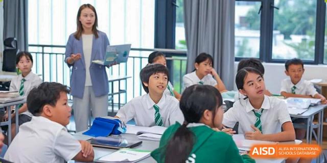 Students in school uniforms focused on their teacher and participating in an interactive classroom lesson at Shen Wai International School.