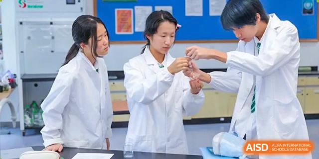 A student wearing a white lab coat carefully conducts a science experiment using laboratory equipment at Shen Wai International School.