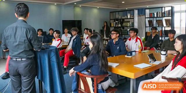 Students in school uniforms sit at a long wooden table during a focused classroom seminar or group discussion at Zhongshan Sanxin School International Department.