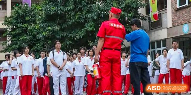 Students gather outdoors to watch a fire safety demonstration conducted by an instructor in a bright red uniform at Zhongshan Sanxin School International Department.