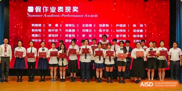 A group of students stands on a stage in front of a red digital screen holding certificates during an academic performance awards ceremony at Zhongshan Sanxin School International Department.