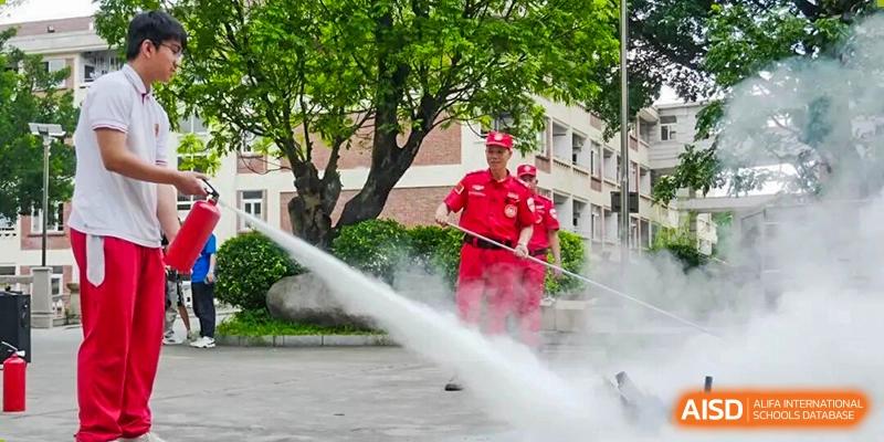 A firefighter in red gear demonstrates how to operate a high-pressure water hose during a safety training session for students at Zhongshan Sanxin School International Department.