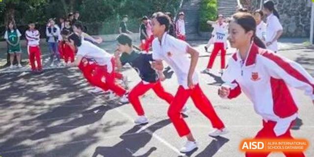 Students in white shirts and red athletic pants participate in a track and field event or outdoor fitness drill at Zhongshan Sanxin School International Department.