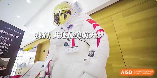 A person dressed in a full white astronaut suit stands in a hallway to promote an exciting aerospace and science program at Beijing Chaoyang KaiWen Academy.