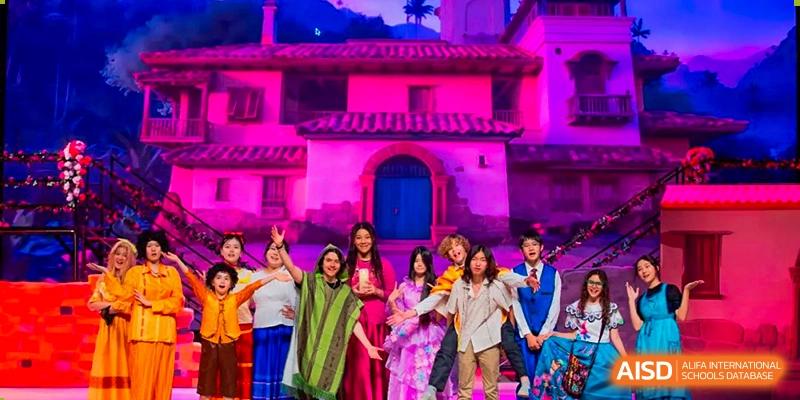 A cast of students in vibrant and diverse costumes performs a theatrical musical production on a stage with professional purple lighting at Beijing Chaoyang KaiWen Academy.