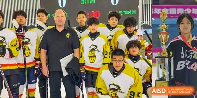 A diverse youth hockey team in yellow, white, and black jerseys poses with their coach on the ice rink during a break in their competitive game at Beijing Chaoyang KaiWen Academy.