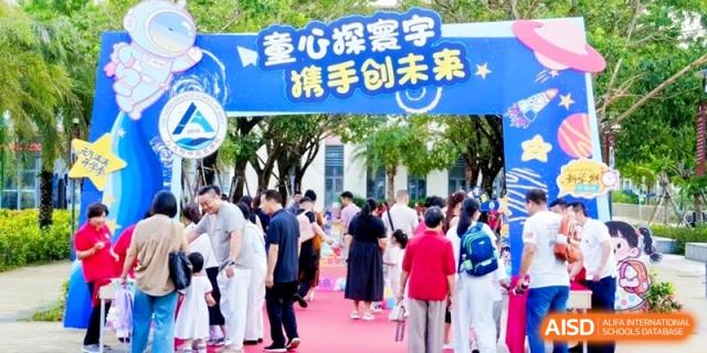 Families and children gather under a colorful blue entrance archway for a vibrant school festival or open house event outdoors at RDFZ Sanya School