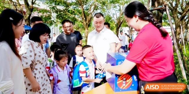 Adults and children interact at a decorated booth during an outdoor school festival or orientation day at RDFZ Sanya School