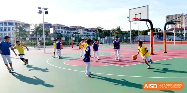 Students in blue and yellow uniforms participate in a team sports activity on an outdoor basketball court at RDFZ Sanya School