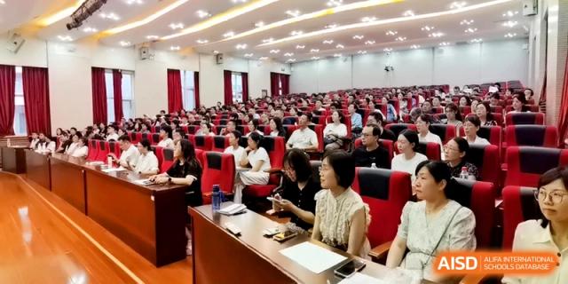 An audience of parents and faculty sits in red chairs during a presentation at the Attached Senior School Of Shandong Normal University.