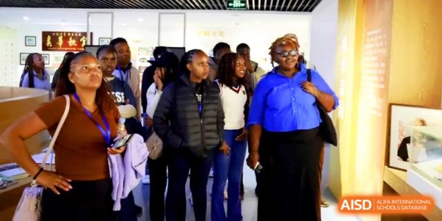 A group of diverse international visitors or students stands together in a hallway at the Attached Senior School Of Shandong Normal University.