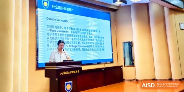 A college counselor speaks at a podium in front of a large informational slide at the Attached Senior School Of Shandong Normal University.