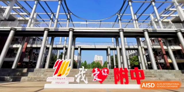 A modern campus structure with a large "I Love You" sign stands under a clear blue sky at the Attached Senior School Of Shandong Normal University.