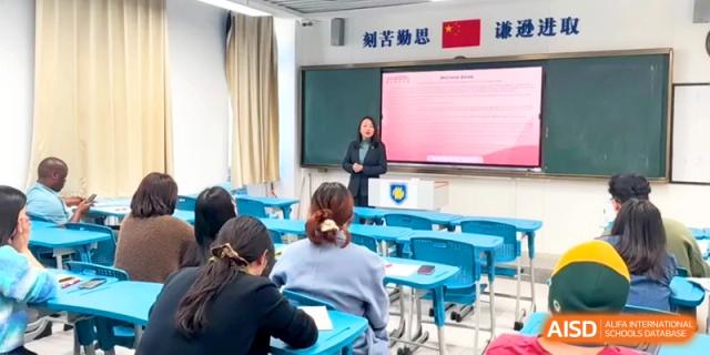 A female faculty member gives a presentation to a classroom of seated colleagues at the Attached Senior School Of Shandong Normal University.