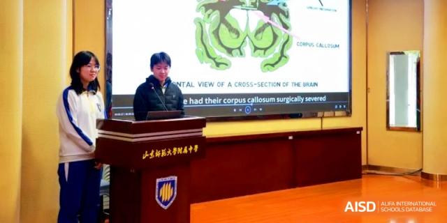 A student delivers a scientific presentation about brain cross-sections from a wooden podium at the Attached Senior School Of Shandong Normal University.