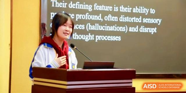A female student speaks confidently into a microphone during a school presentation event at the Attached Senior School Of Shandong Normal University.