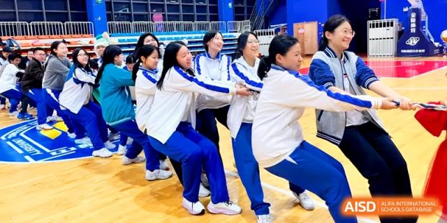 A group of female students in school uniforms compete in a tug-of-war match at the Attached Senior School Of Shandong Normal University.